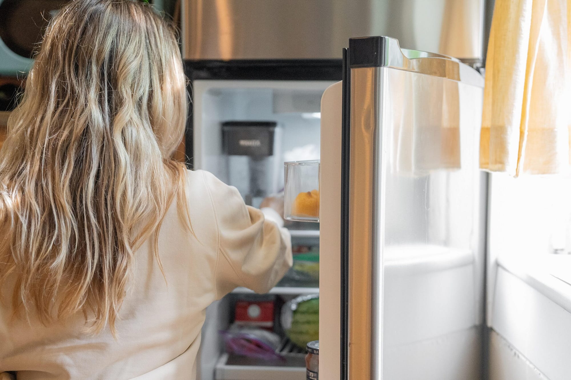 Woman opening fridge and reaching inside