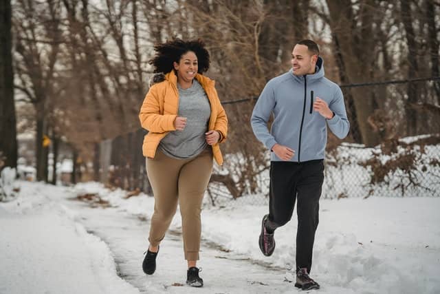 Happy woman and man running outside during winter.