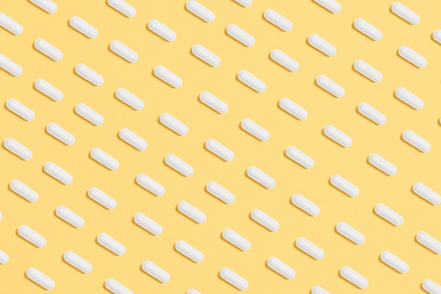 Many white pills on a yellow background
