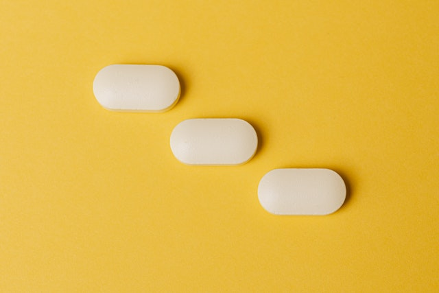Three white pills on a yellow background.