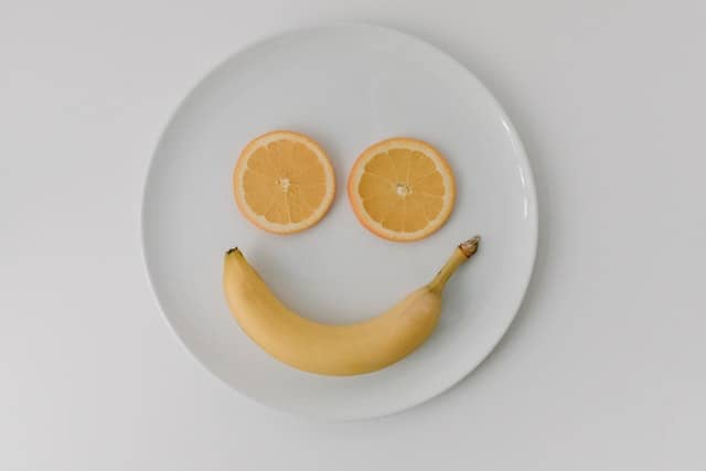 Two orange slices and a banana form a smiley face.