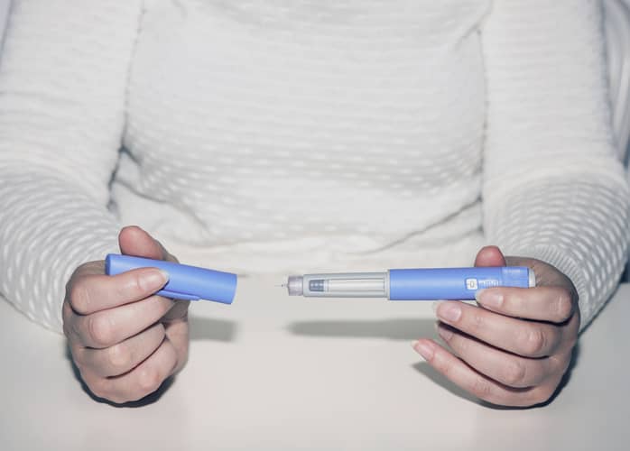 Woman holding an injectable pen for weight loss medication like Wegovy.
