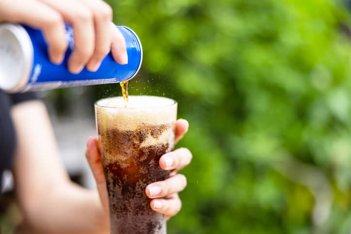 pouring soda from a can to a glass