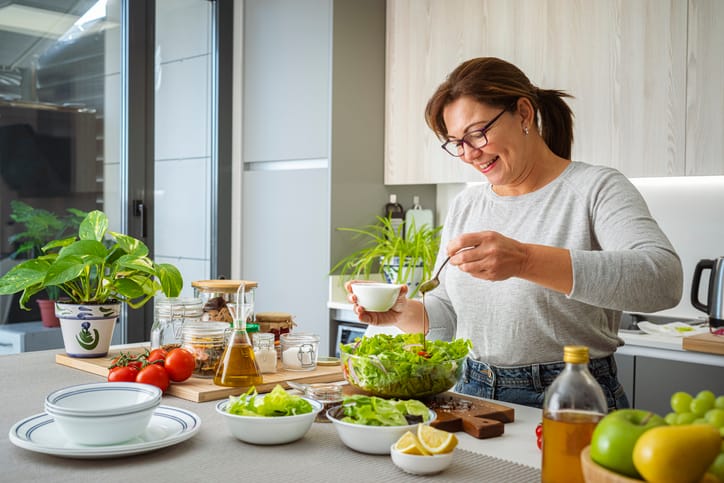 Smiling woman preparing fresh salad